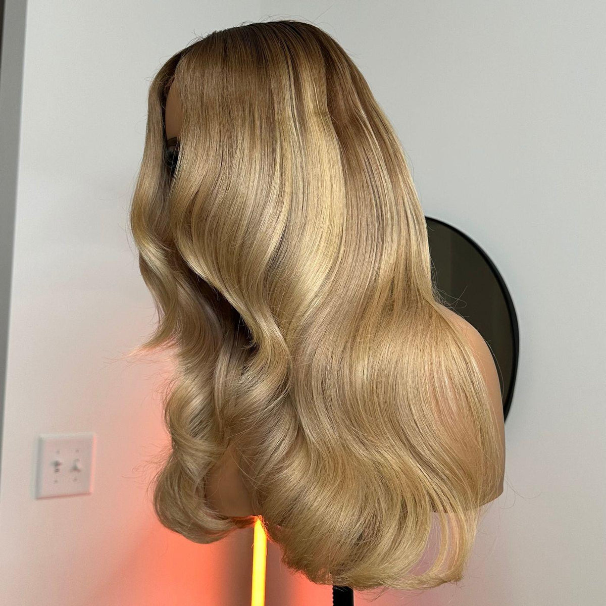 Dark root blonde wig on a mannequin head against a neutral background